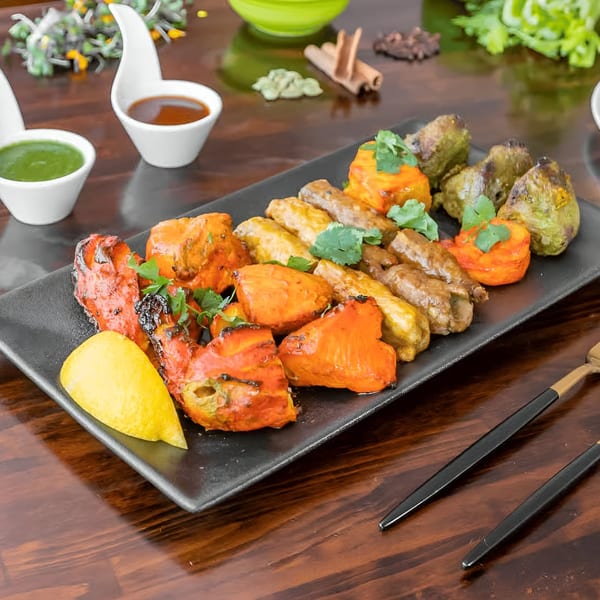 Star of India's Indian platter with chicken tikka, seekh kebab, and paneer tikka, garnished with lemon and cilantro.
